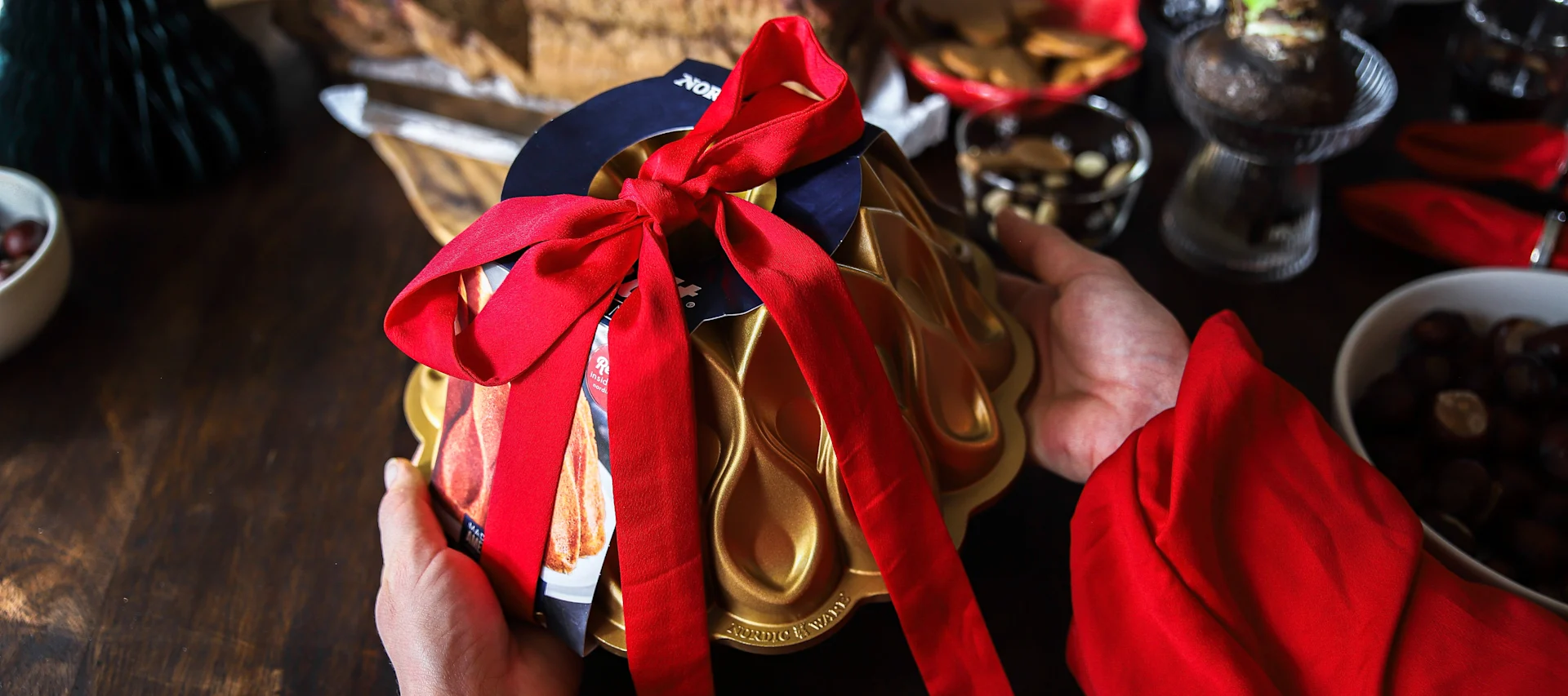 A baking pan from Nordic Ware with a red tied ribbon around it, presented as a Christmas gift idea.
