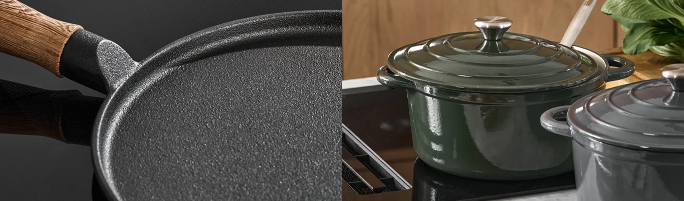 Close-up of a black cast iron pan and two enameled cast iron pots (one green, one grey) on a stovetop.