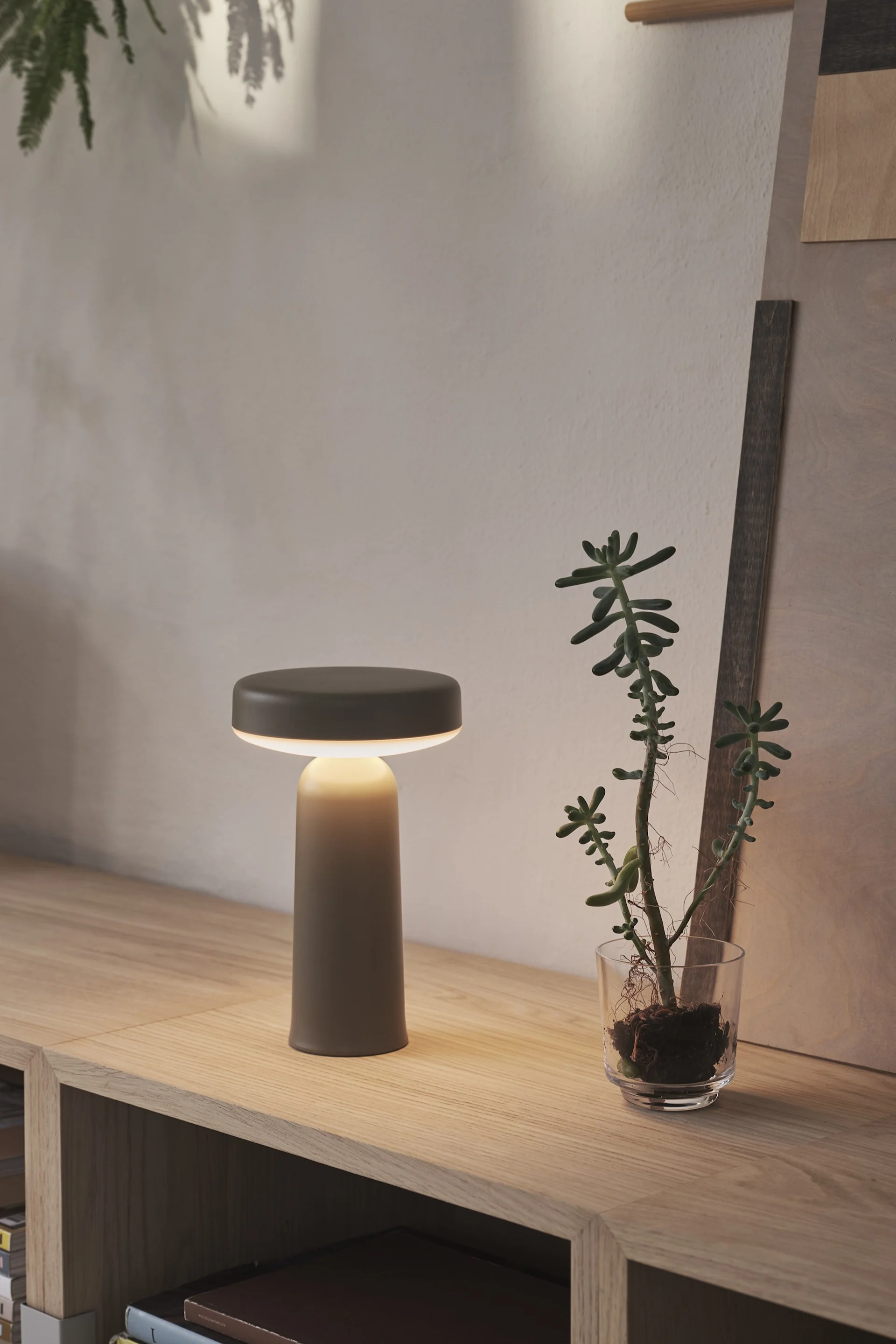 The silver, portable Piton table lamp from Muuto hangs on one of four hooks on the wall.