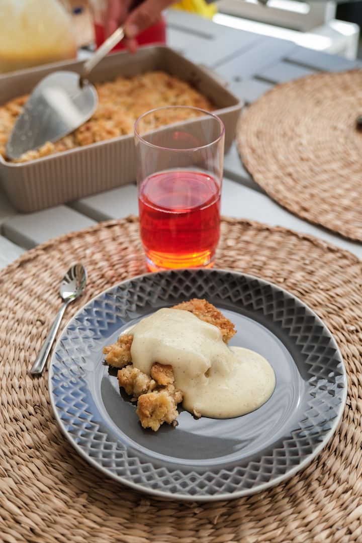 Picture showing Coffee Moore plate in grey with baked apple pie and custard on it, red juice in Saga drinking glass from Sagaform.