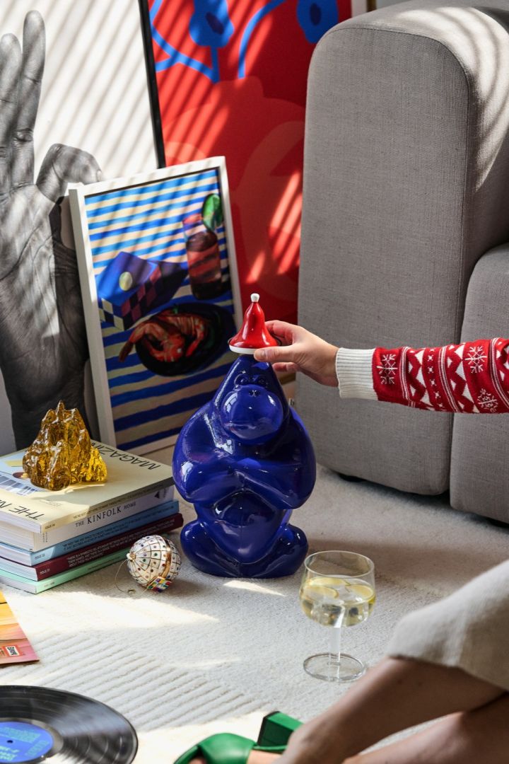 A hand places the Santa hat from Kay Bojesen on the head of Gabba Gabba from Kosta Boda, the perfect addition to any vintage Christmas decor. 