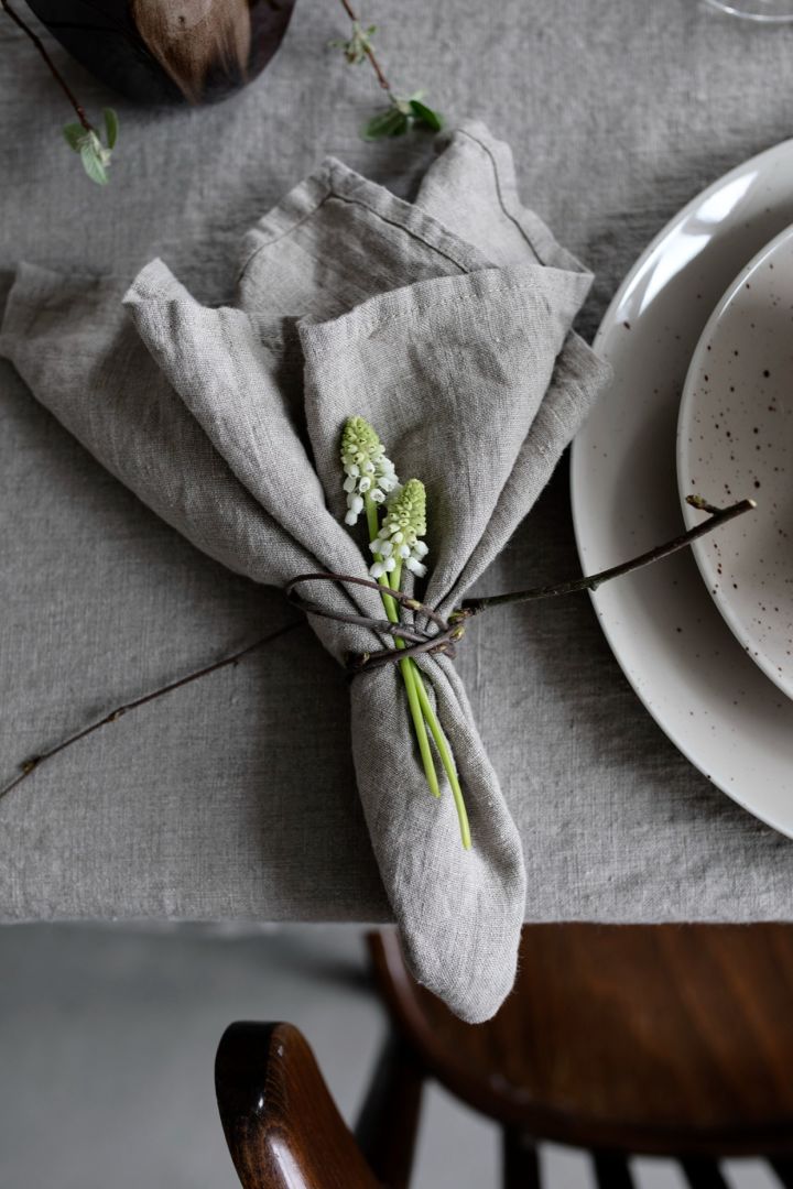 A simple rustic napkin fold next to a place setting on the table. 