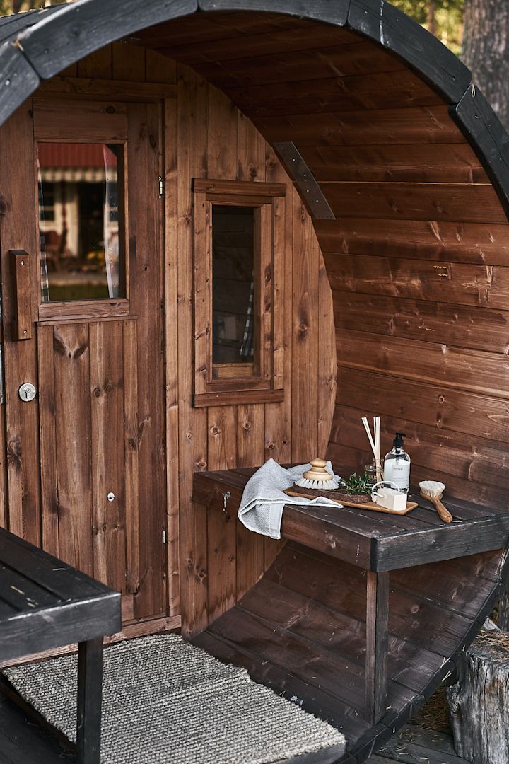 Make sure to add a trip to a Swedish sauna to your summer bucket list. Here you see a wooden sauna with a collection candles and brushes outside.  