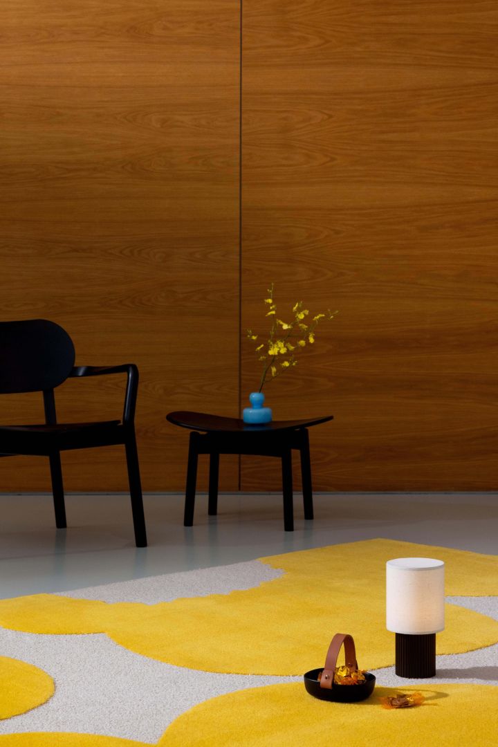 The blue flower vase stands on a yellow and beige Unikko rug from Marimekko. 