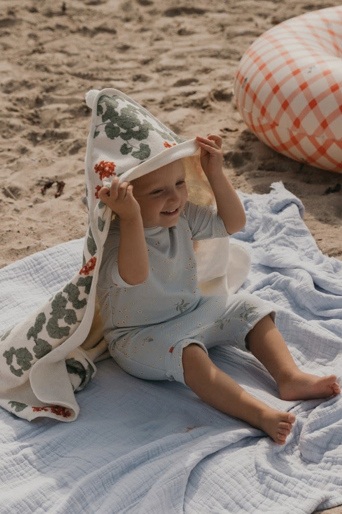 A baby lays on a towel with a hood in a matching baby grow from Garbo&Friends - perfect baby shower gift ideas. 