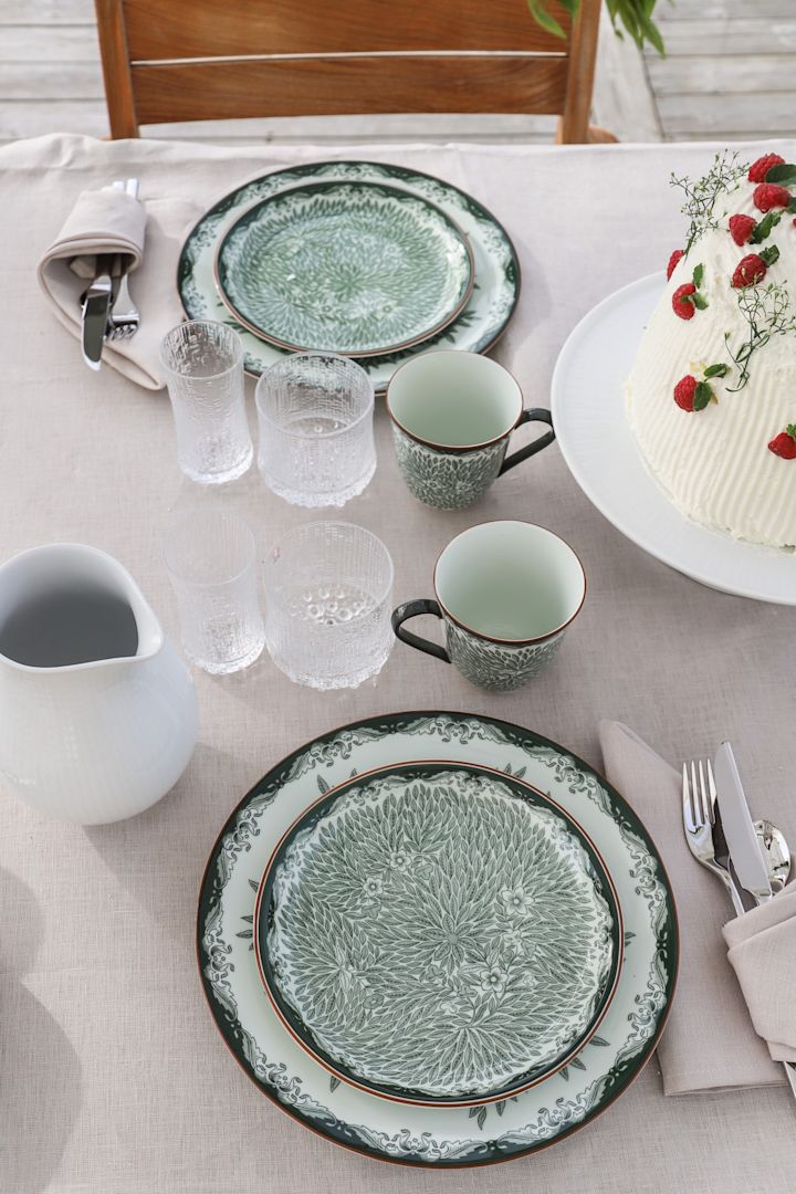 Traditional midsummer party ideas include alfresco dining. Here you see the green Ostindia and Ostindia Floris series on the table with the ultima thule glasses from Iittala. 