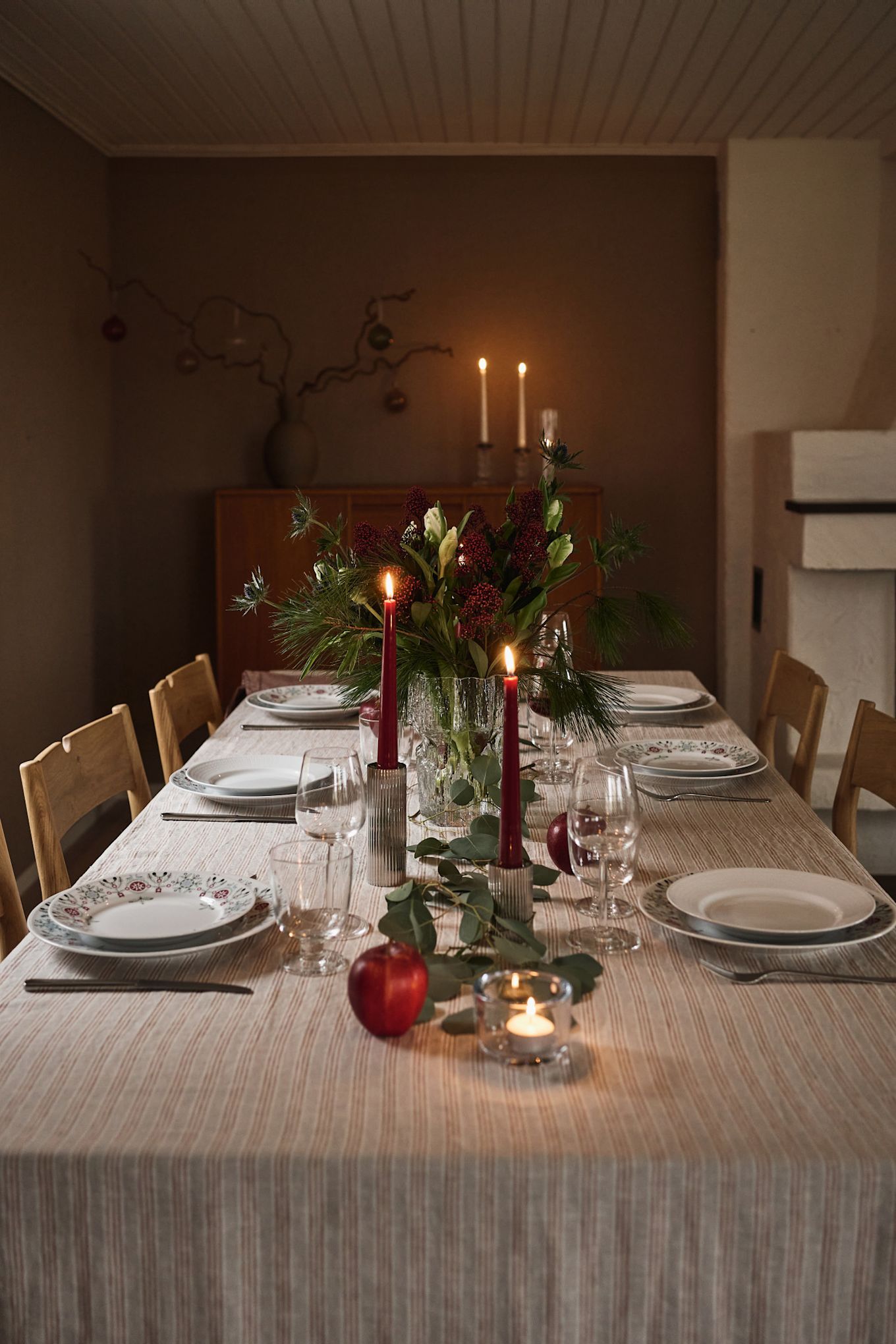 An atmospheric and simple Christmas table setting idea with red candles and printed Christmas tableware. 