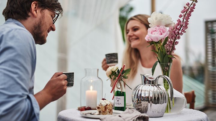 Set a romantic table for Valentine's Day with pastries, coffee and flowers on the table.