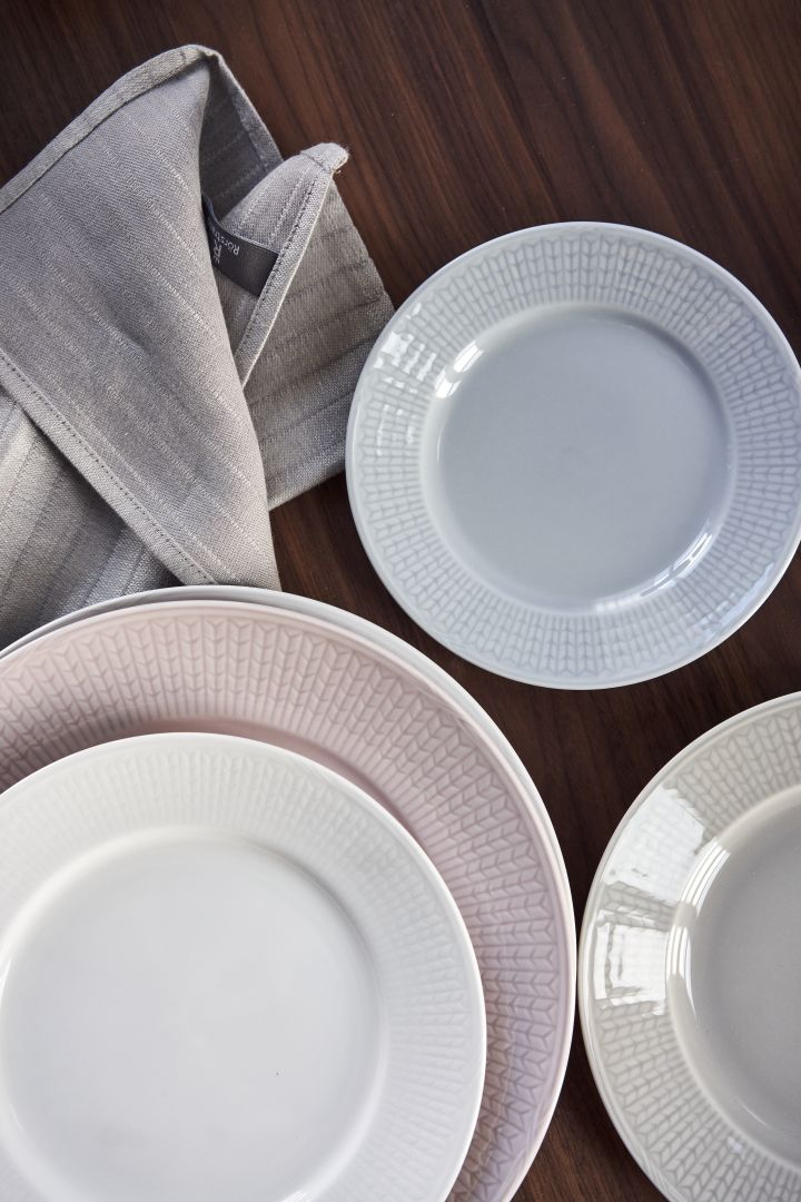 Swedish Grace plates in white, pink, blue and grey on a dark wooden table. 