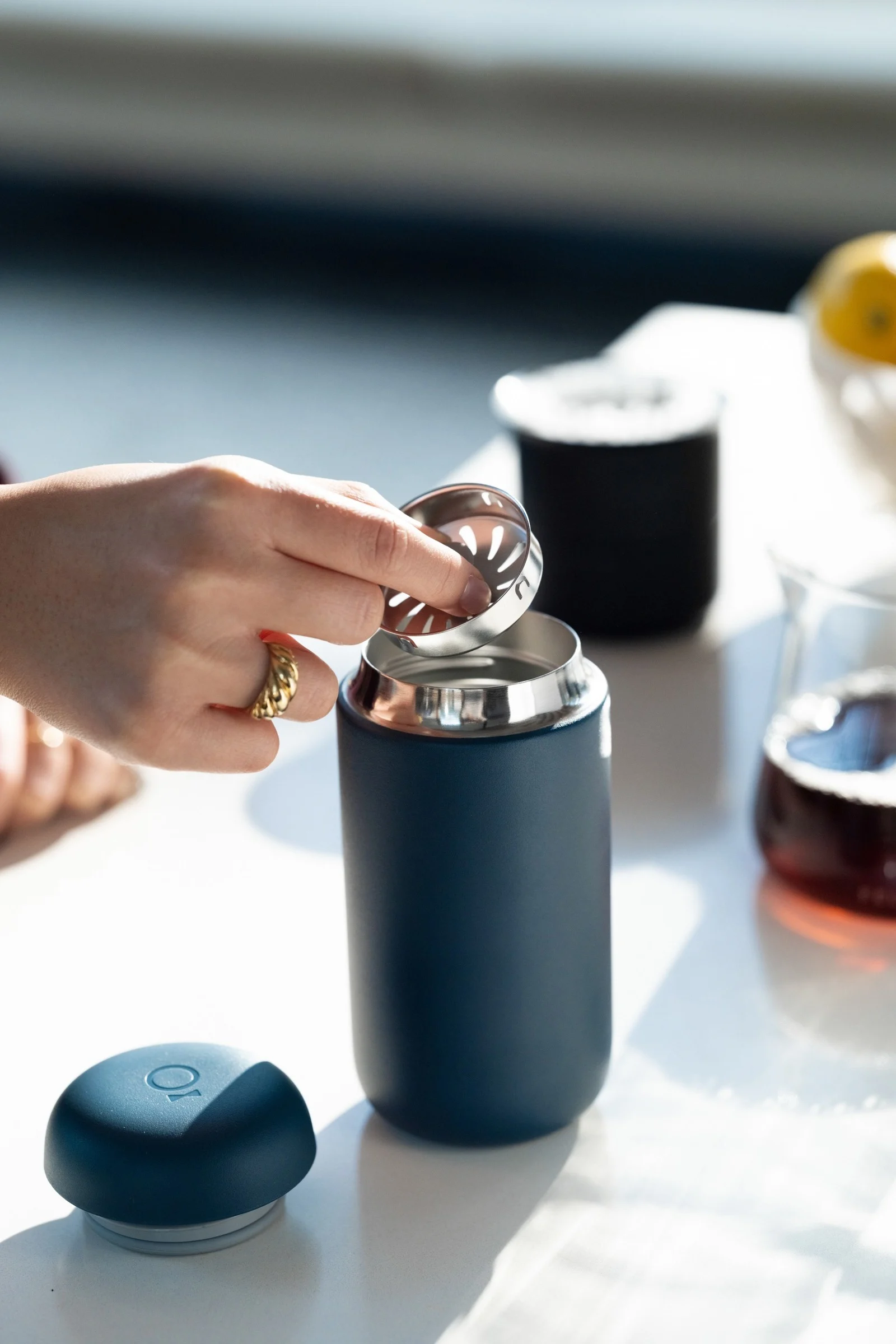 Simply take your coffee with you - with the blue Carter thermo mug from Fellow, shown here on a kitchen table.