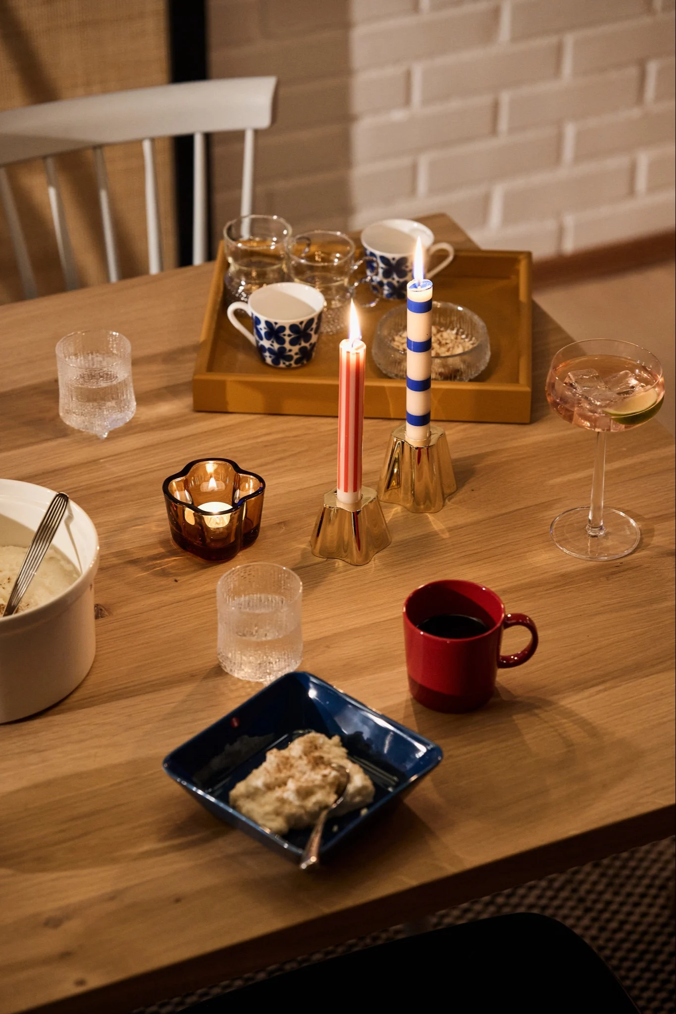 A festive red and blue Nordic Christmas table with a blue bowl with Ris a la Malta, a matching red mug and blue and red candles.