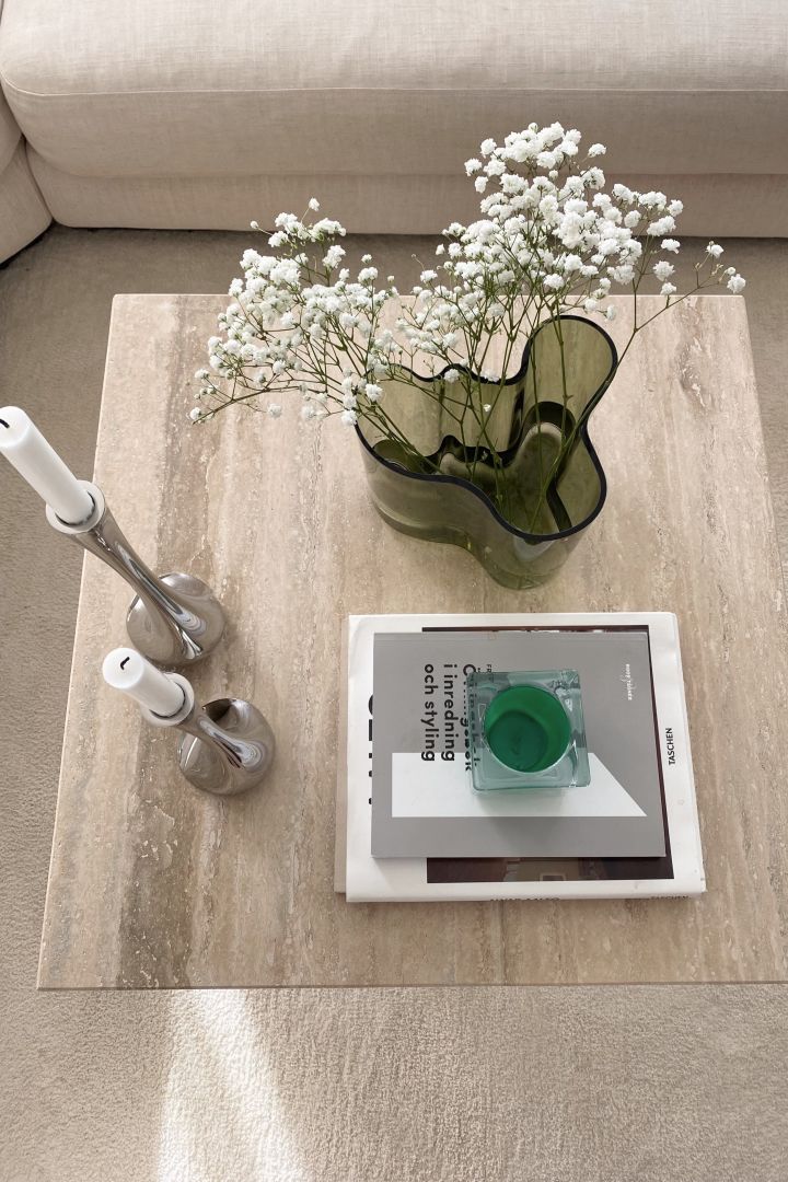 Create a cosy hygge living room with natural elements like a stone coffee table or a green vase, here you see the Alva Aalto Vase from Iittala. 