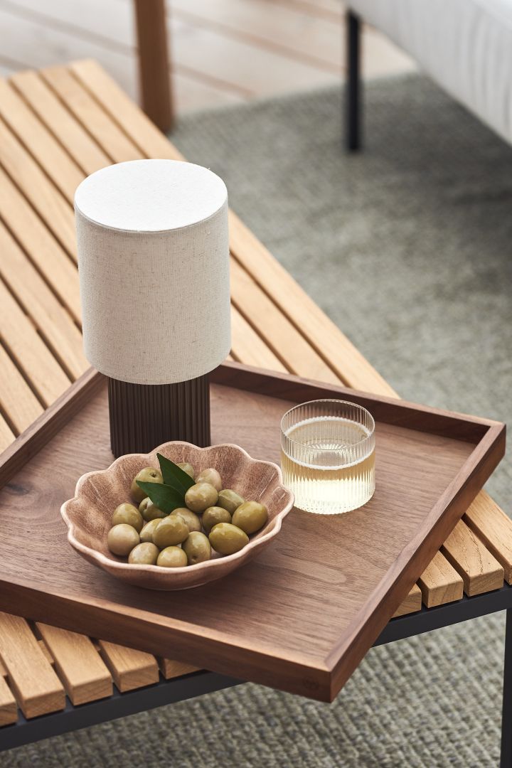The portable Manhattan table lamp from &Tradition outside on coffee table on a balcony. 