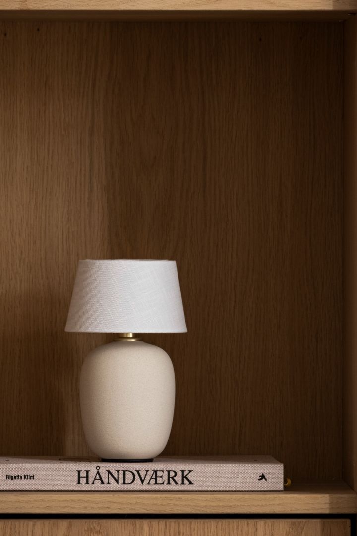 This season's trendiest mushroom lamp - the portable Torso table lamp from Menu seen here in a wooden bookshelf. 