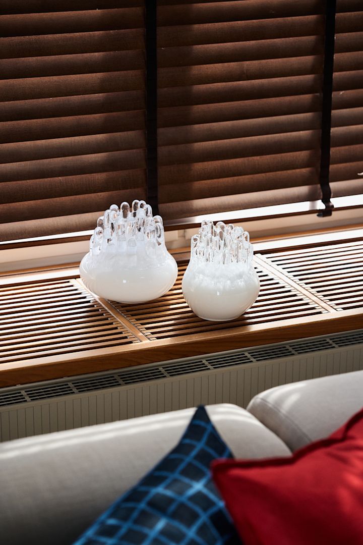 Autumn design trends 2025: Two white Polar candle holders from Kosta Boda stand on a windowsill.