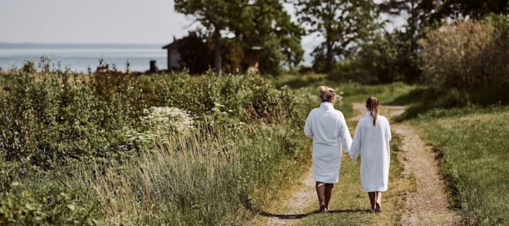 A woman and a girl walk to the beach wearing white bathrobes. A dip in the sea is a must do on any Swedish summer bucket list. 