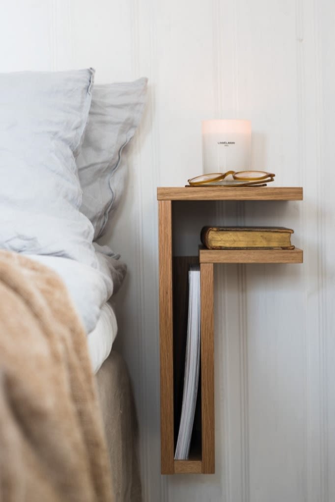 The F-shelf from Maze facing away from the bed with books, eye glasses and a candle. 