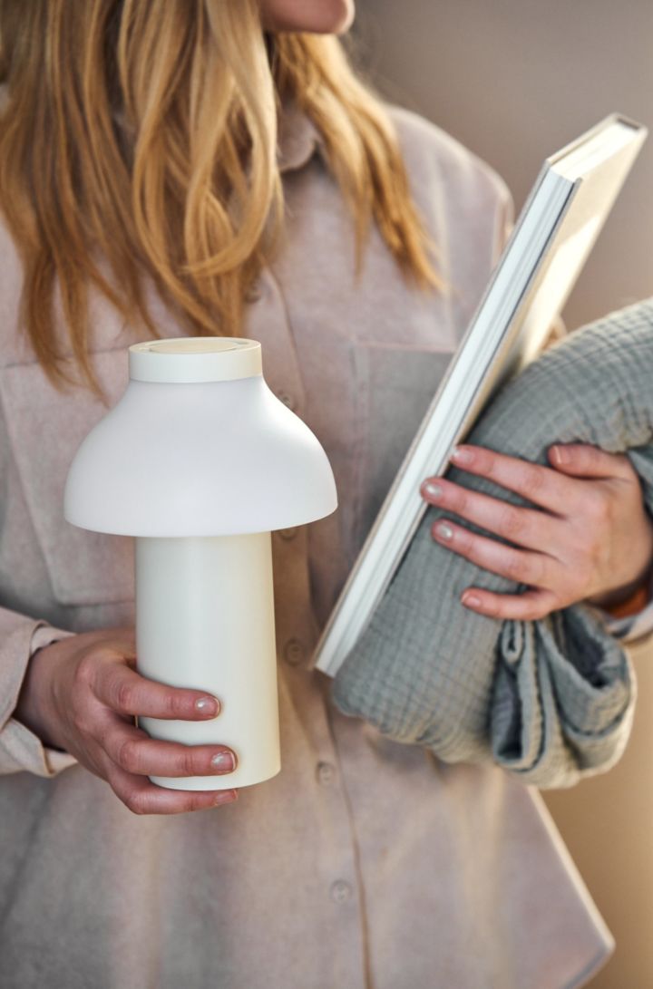 The cordless table lamp PC portable from HAY is carried to a cosy corner.