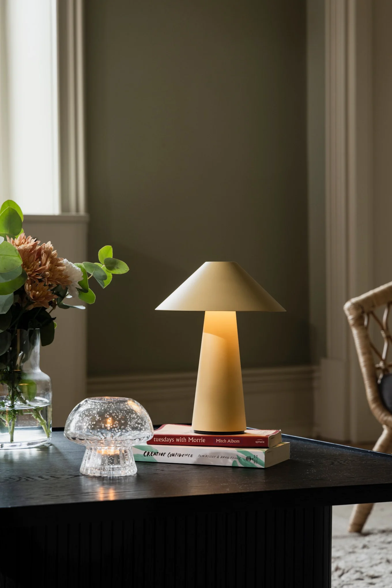 The cordless table lamp PC portable from HAY is carried to a cosy corner.