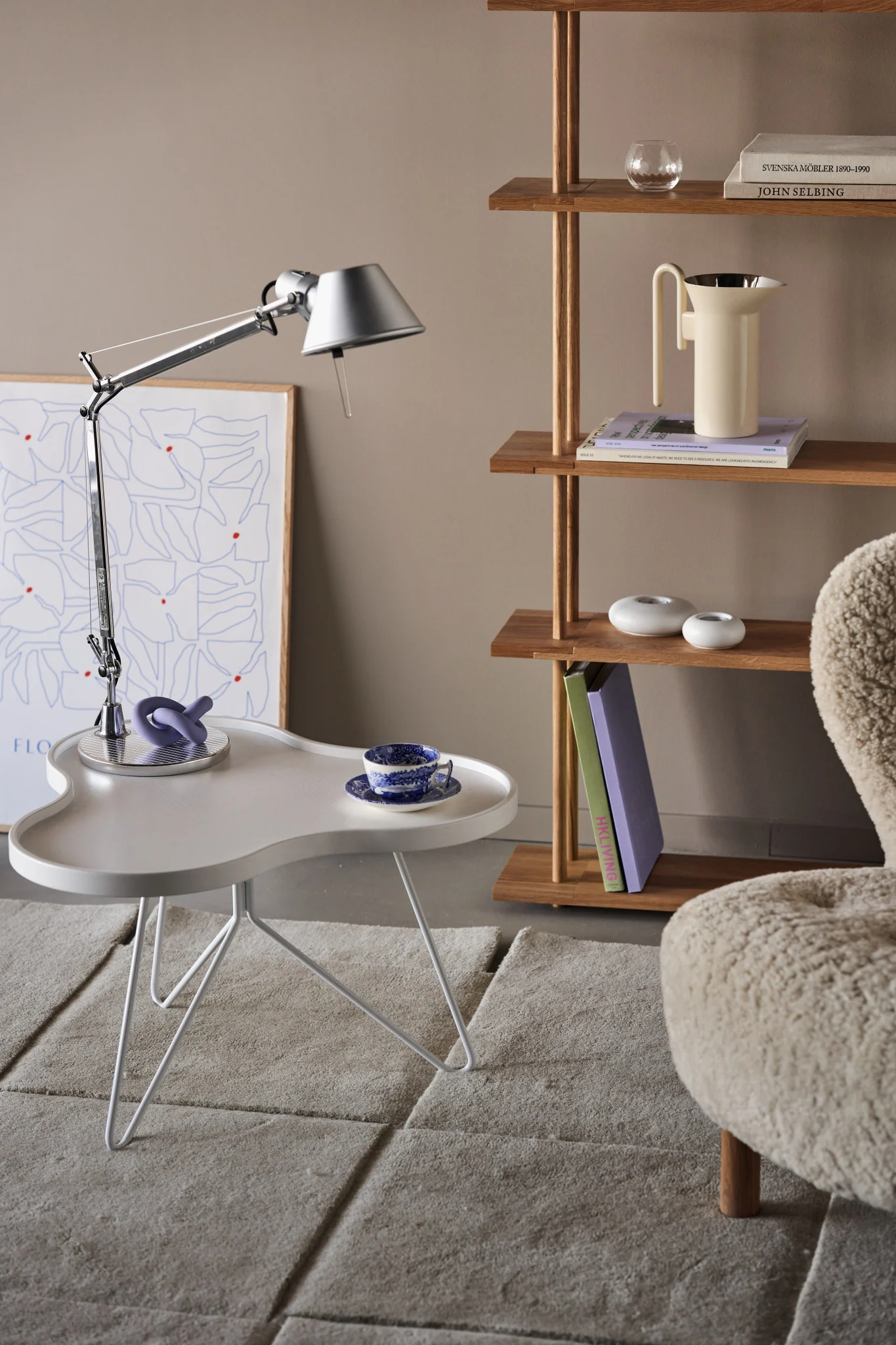 The stainless steel Tolomeo lamp with an adjustable arm stands on a white table with purple accents.
