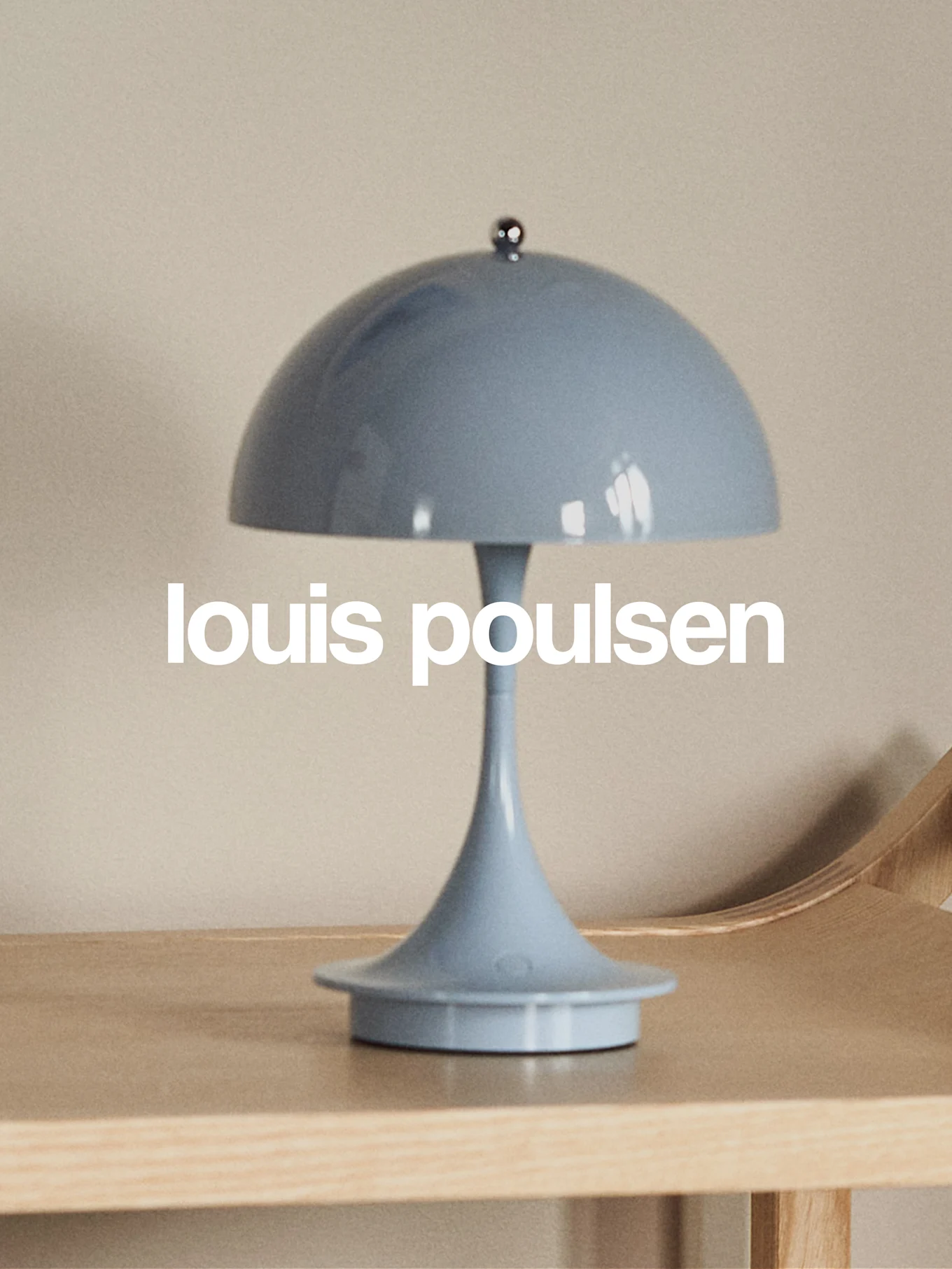 Light blue mushroom-shaped table lamp on a wooden surface with 'louis poulsen' text.
