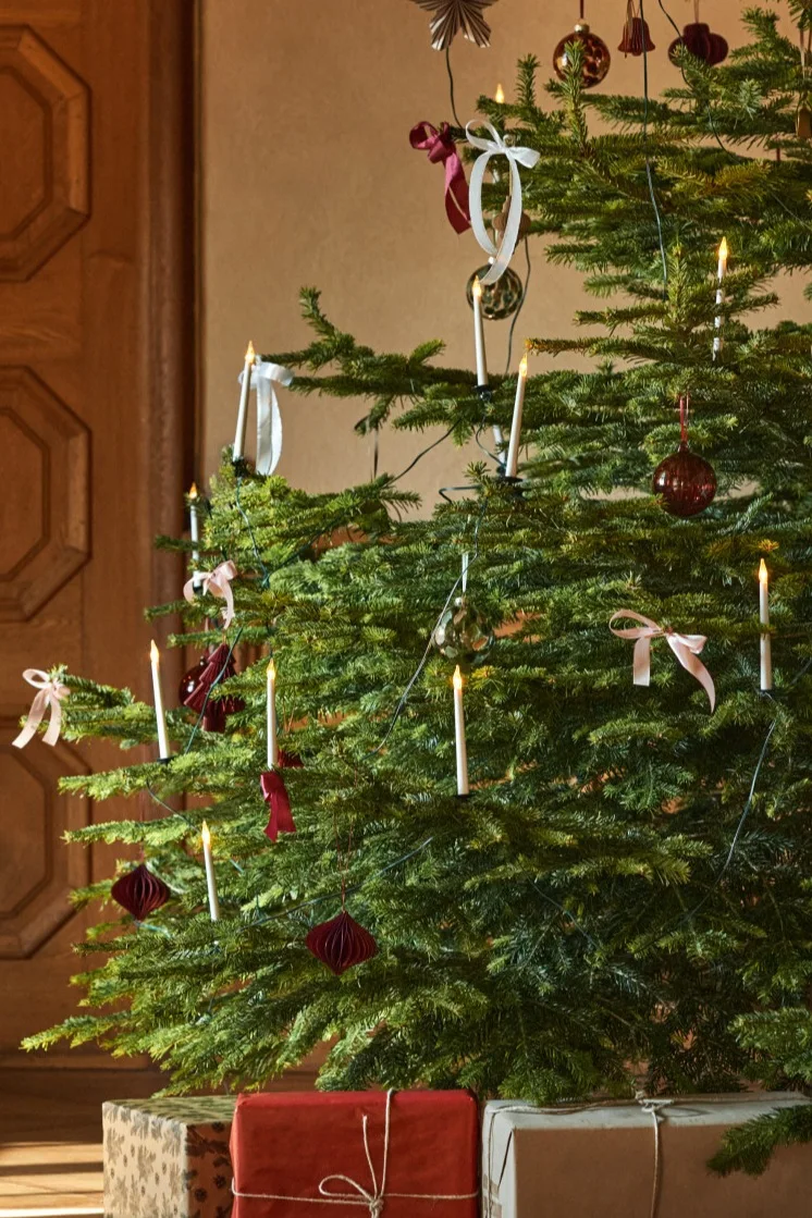Traditional Christmas tree decoration ideas include things like the electric tree candles and bows you see here on a tree with red, white and gold decorations. 