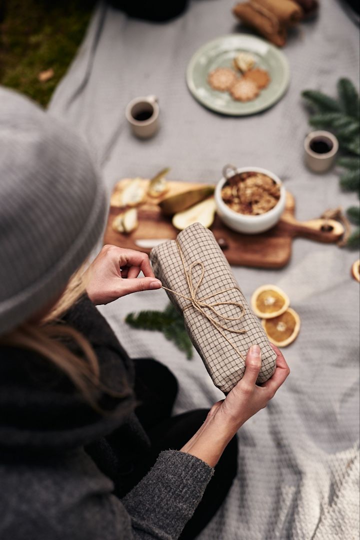 A Christmas present, wrapped in a tea towel with string, is carefully opened.