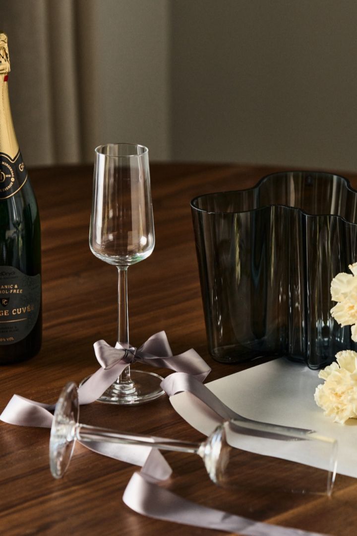 Creative gift ideas for an engagement. Here you see the Essence champagne glasses from Iittala with a bottle of champagne and accompanied by the Alvar Aalto vase. 