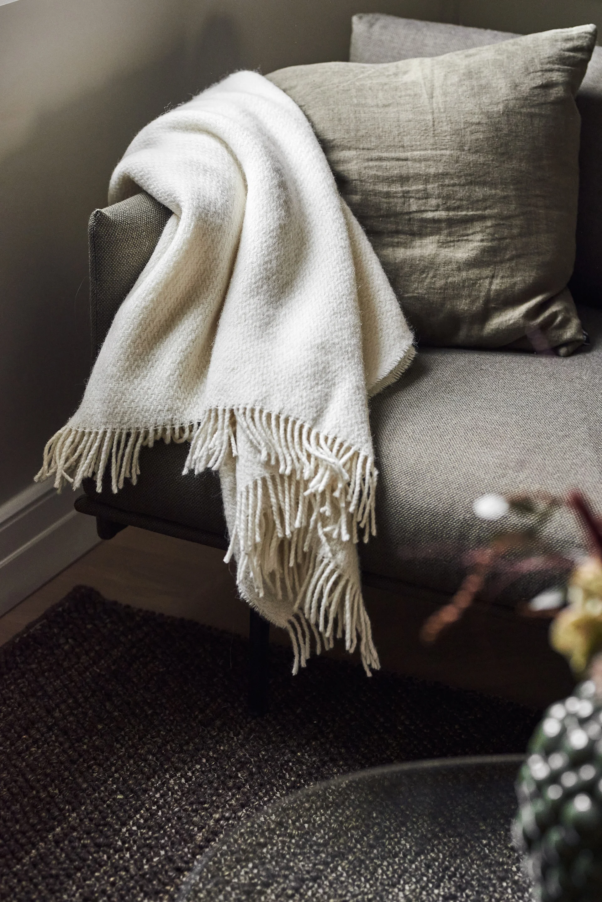 A cosy blanket makes an excellent Mother's Day gift. Here you can see the white Sandstone blanket from Scandi Living lying over a couch.
