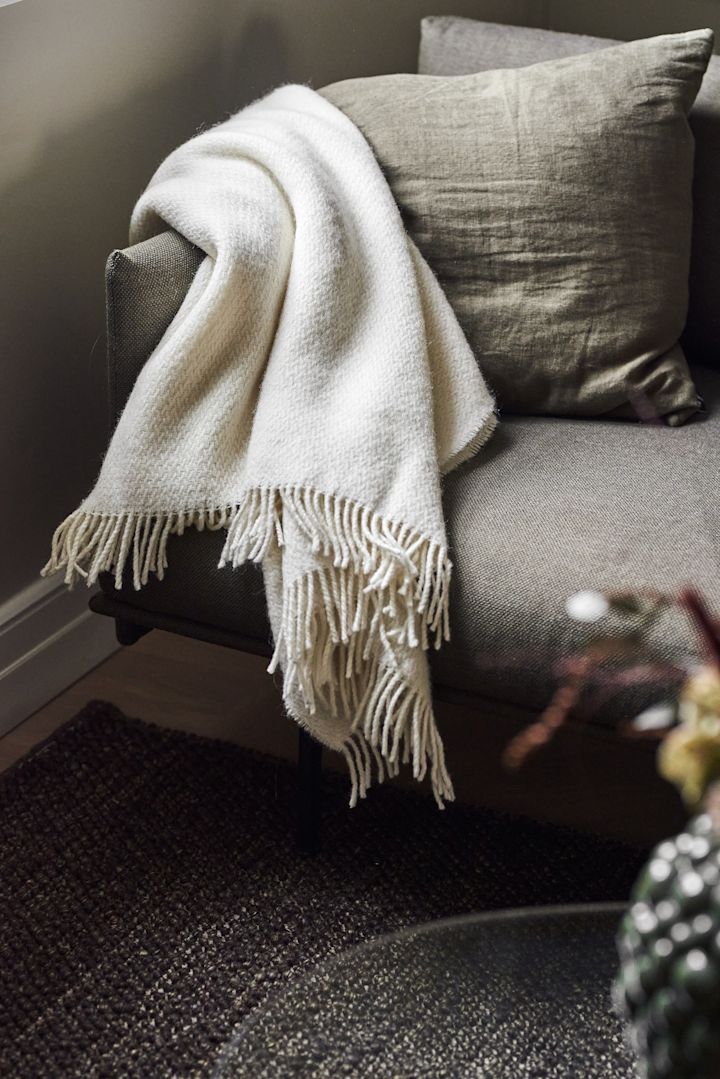 A cosy blanket makes an excellent Mother's Day gift. Here you can see the white Sandstone blanket from Scandi Living lying over a couch.