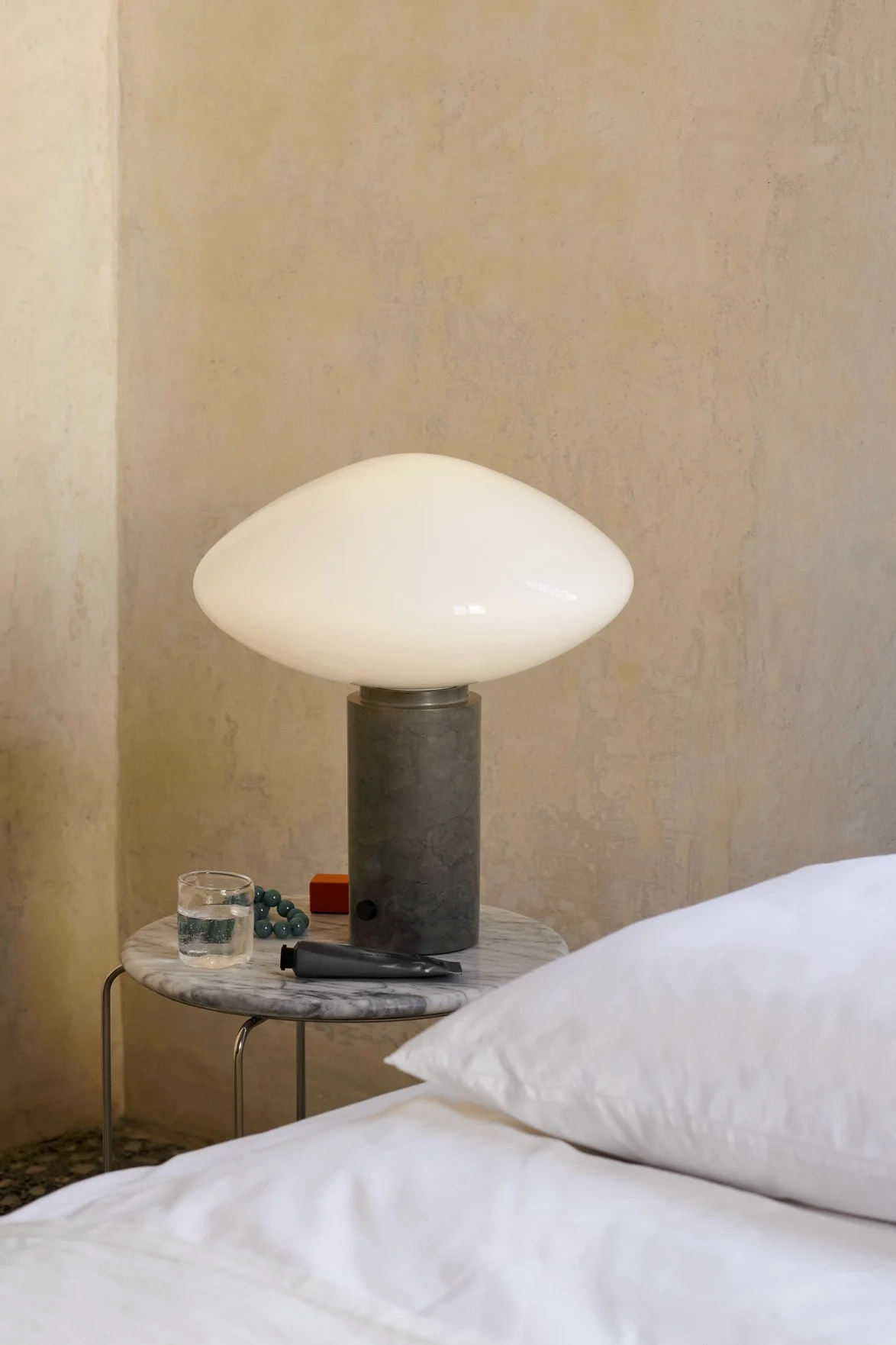 Autumn interior design trends 2025: The Mist table lamp with green marble base from &tradition stands on a side table next to the bed.