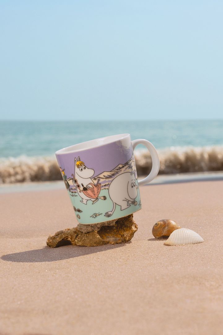 The Moomin mug Summer 2025, ‘Beach Day’ stands on a sandy beach.