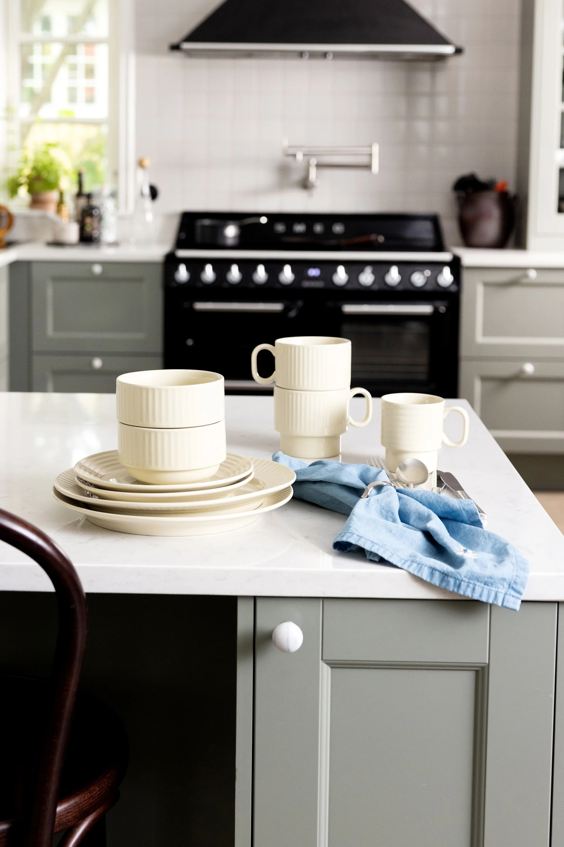 Beige-coloured crockery, plates, cups and bowls from Sagaform's Coffee & more collection are displayed on a kitchen sideboard.
