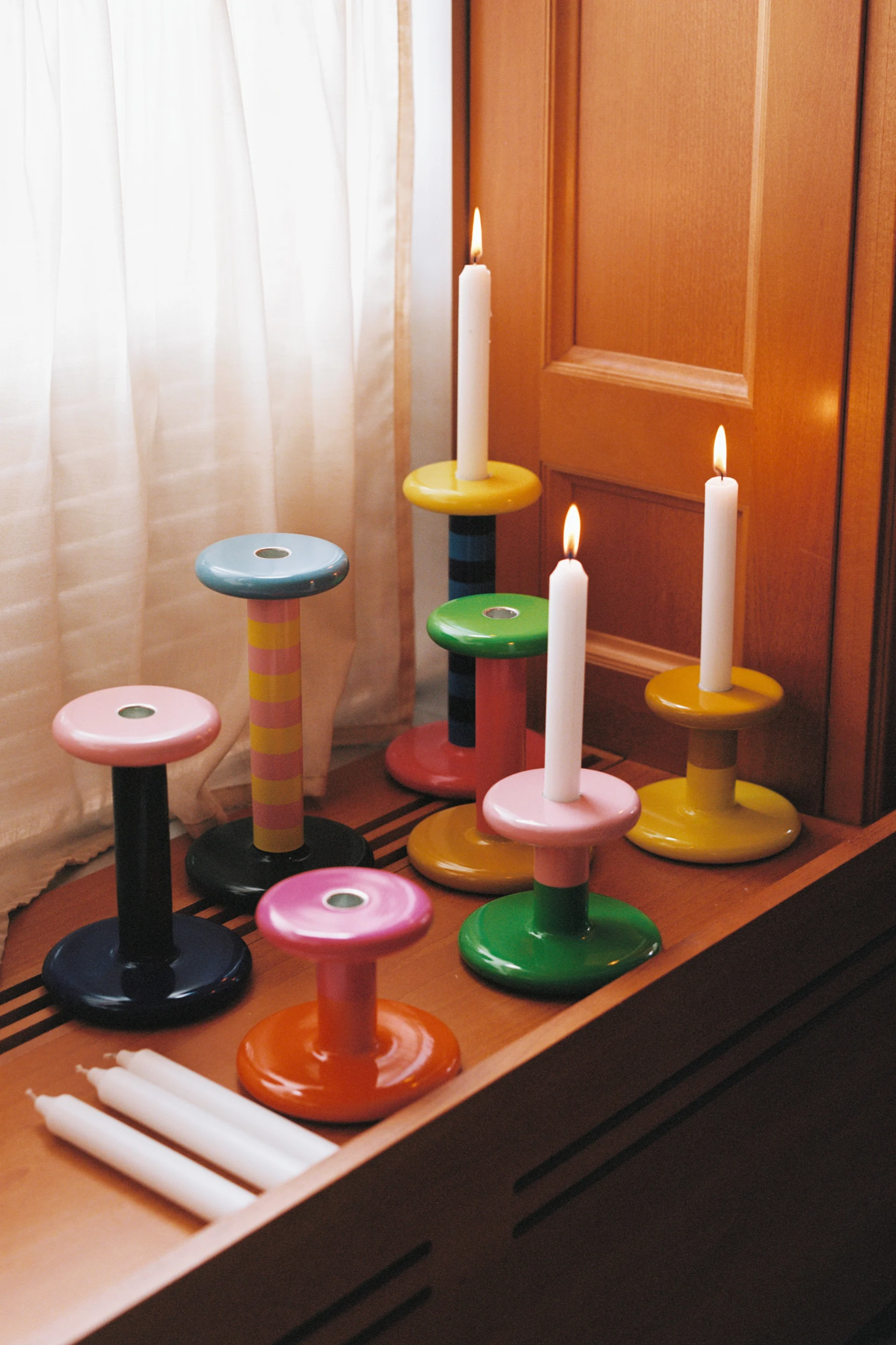 Colorful candle holders on a windowsill with three lit candles, a glimpse of the 2026 interior trends.