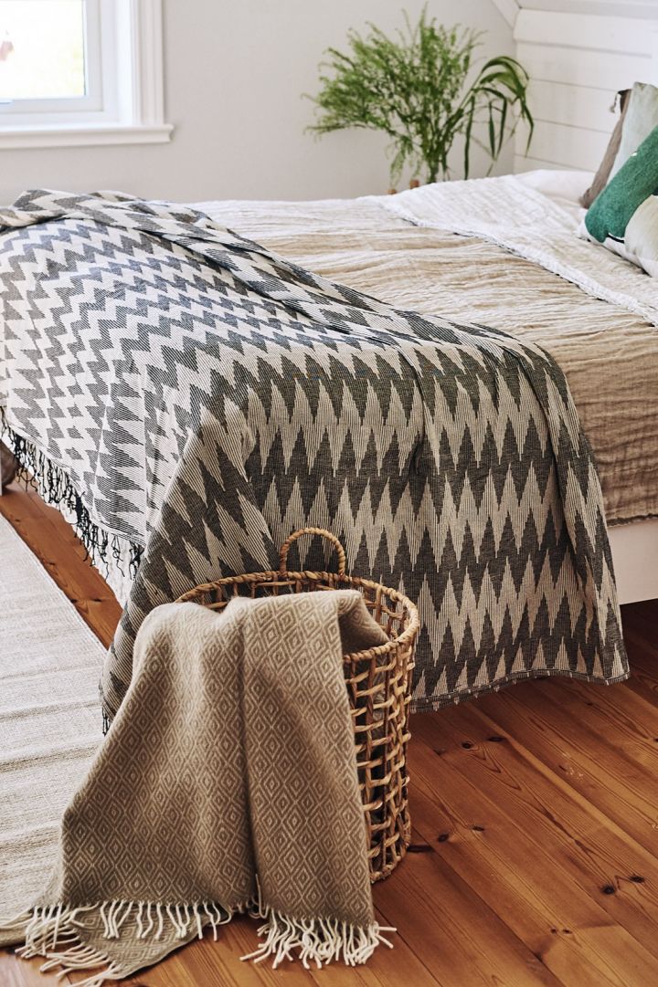 A bedroom decorated in Scandinavian style with soft textiles and pillows in beige shades is a perfect place for a luxury breakfast in bed. Here you see Salt wool blanket from Scandi Living in Ernst's wicker basket.