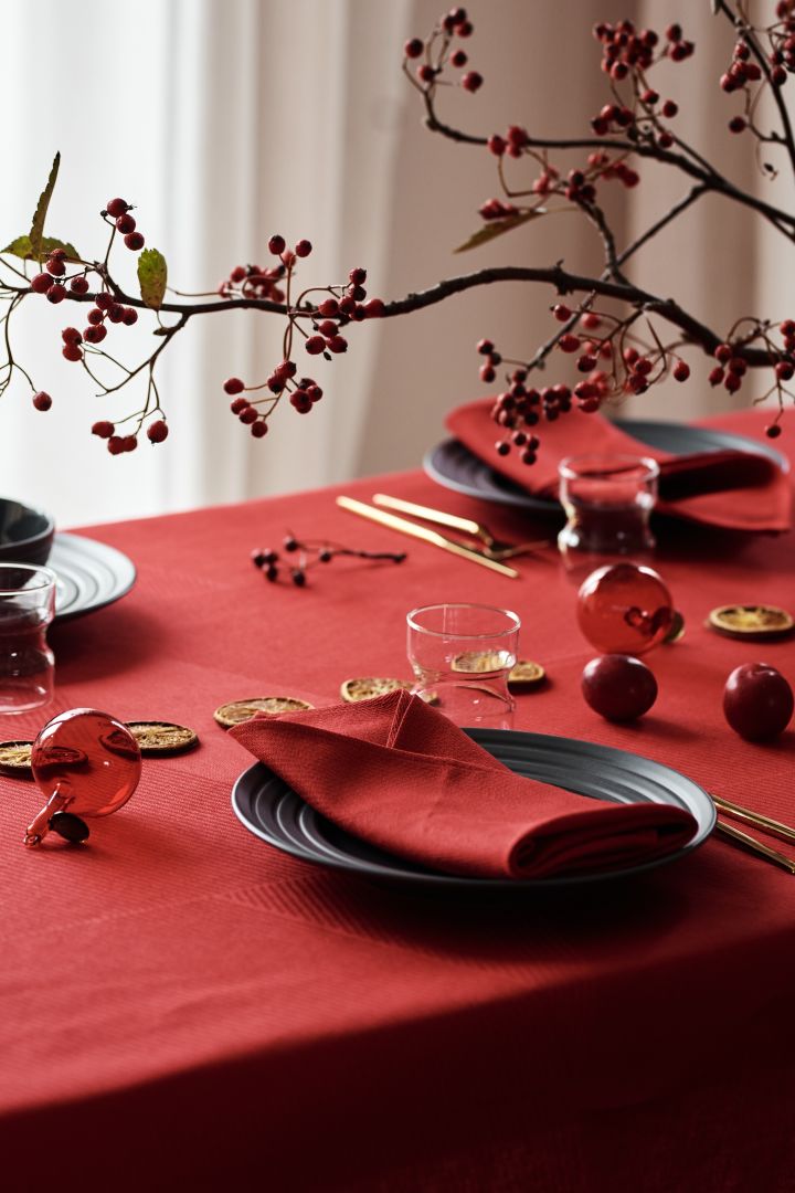 A modern Christmas table setting with red linen napkins, red linen cloth and dark gray Lines porcelain from NJRD.