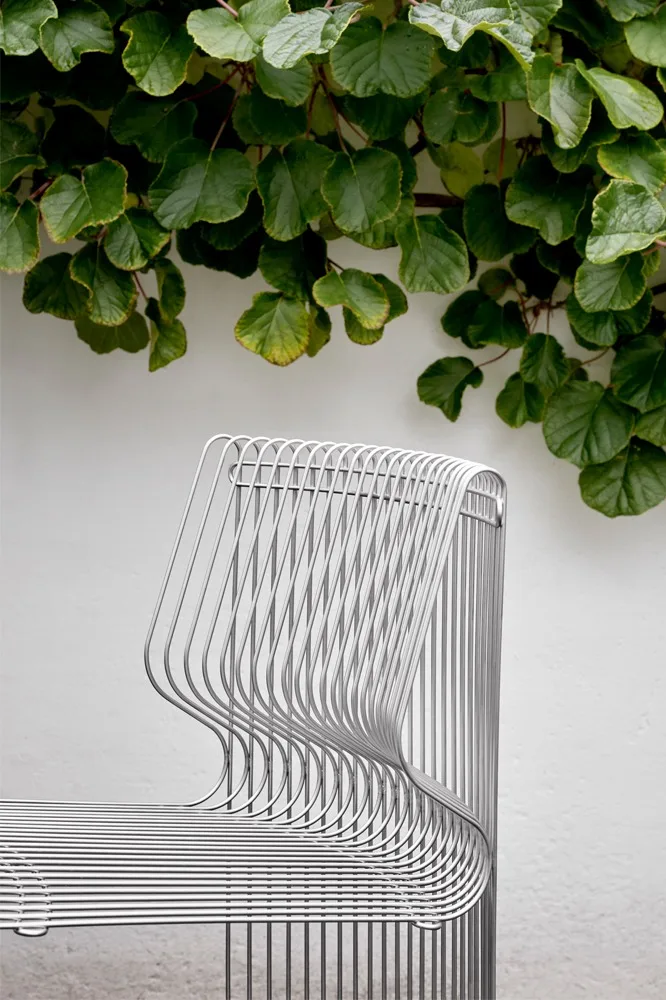 Part of the Panonova modular sofa stands outdoors, framed by climbing plants.