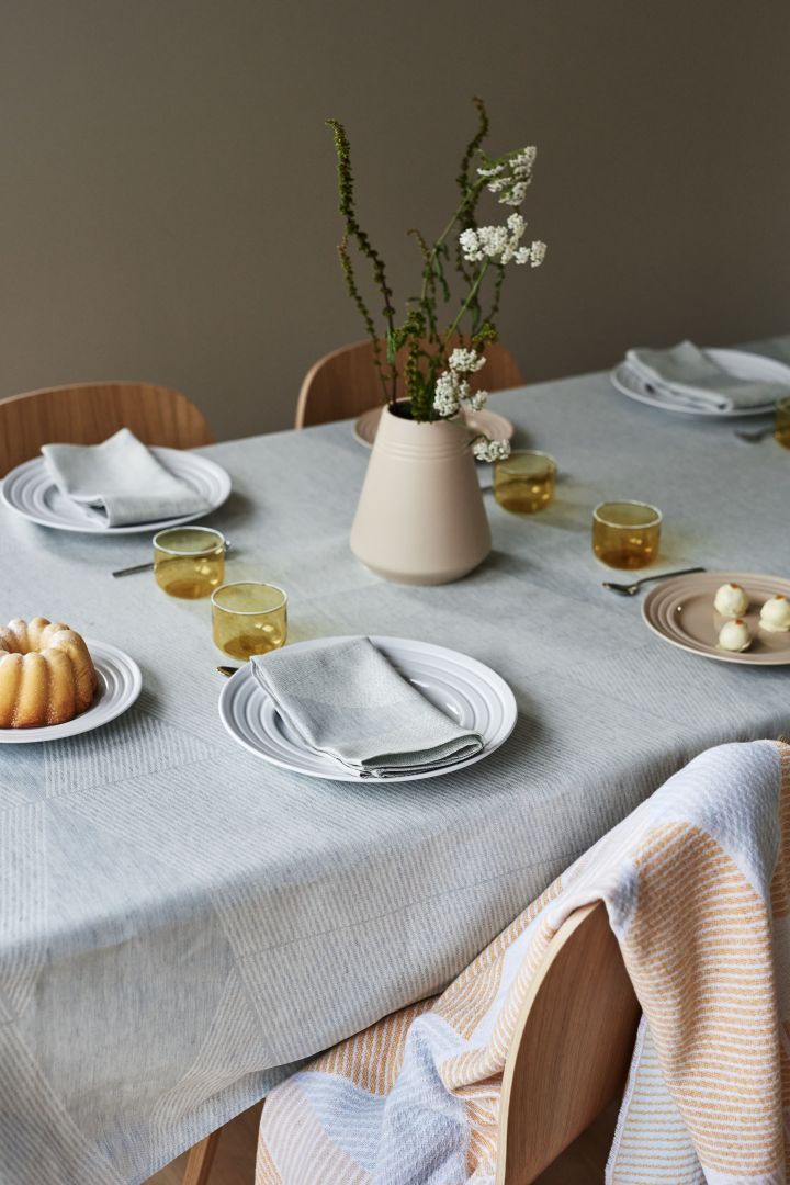 An elegant table setting idea with soft pastels from NJRD with a blue tablecloth and a blue and yellow throw.