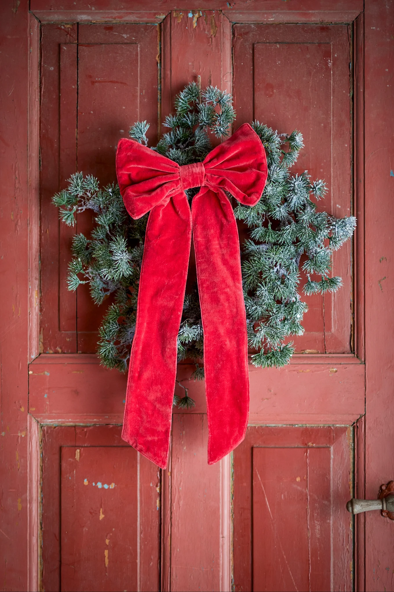 Christmas decorations 2026 - a red bow hanging on a red door with a wreath.
