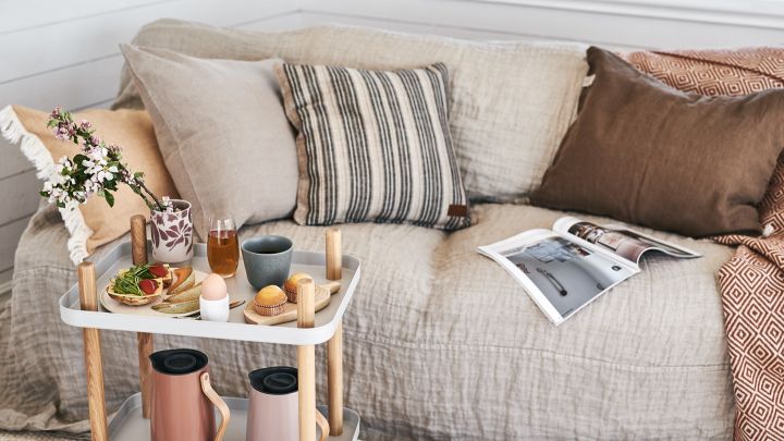A luxury breakfast is served on the side table from Normann Copenhagen and the sofa invites you to relax with soft pillows from ERNST and a warm terracotta blanket