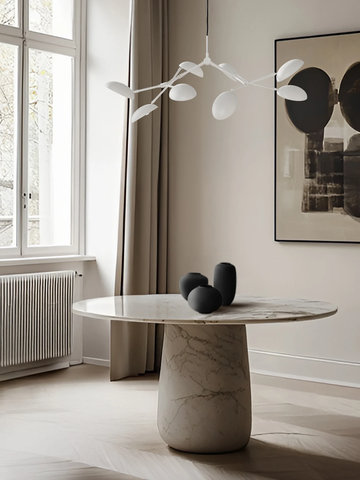 Modern dining room with a round marble table, black vases, and a white leaf-shaped chandelier.