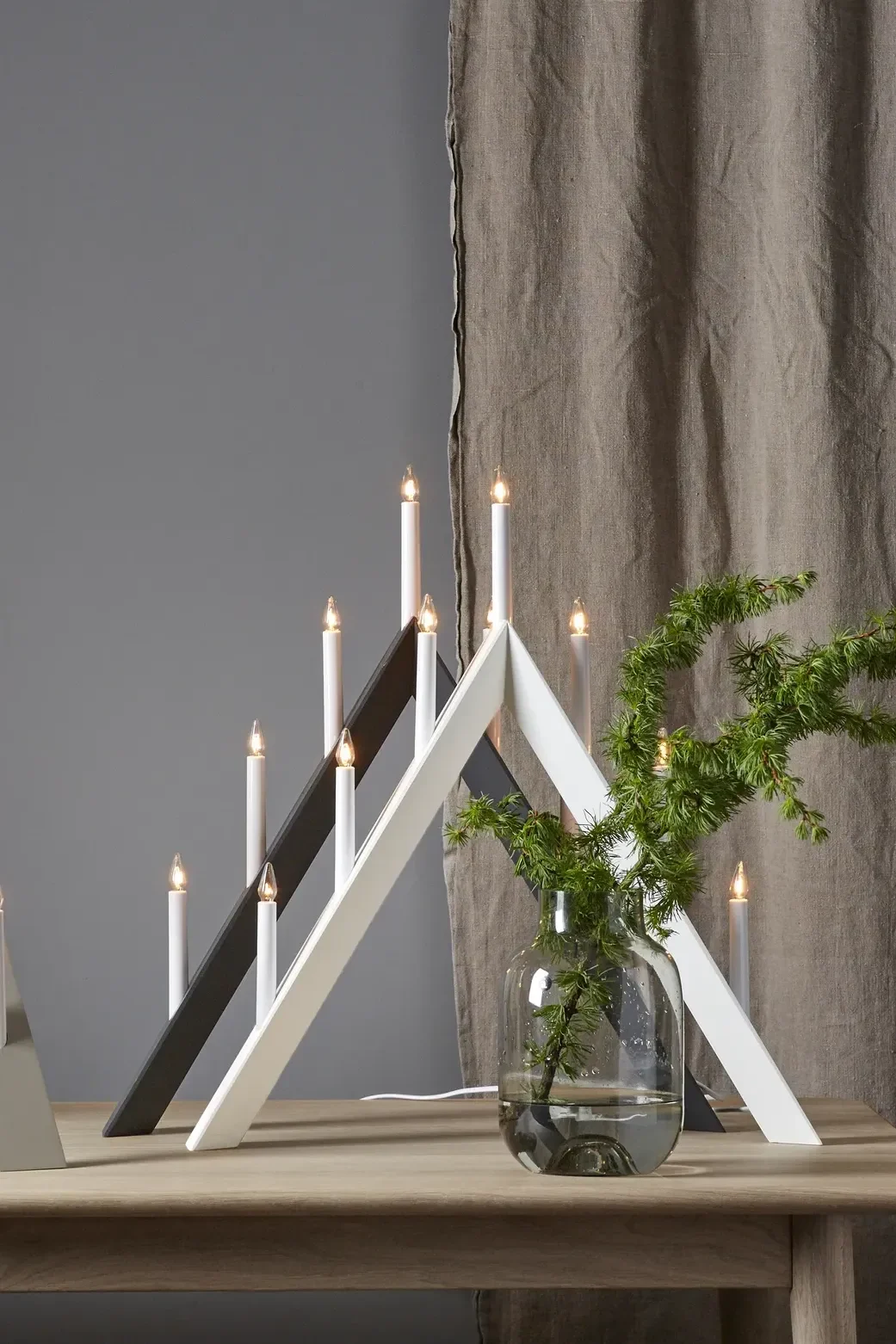 The Arrow Christmas candle arch from Star Trading in white stands on a sideboard. 