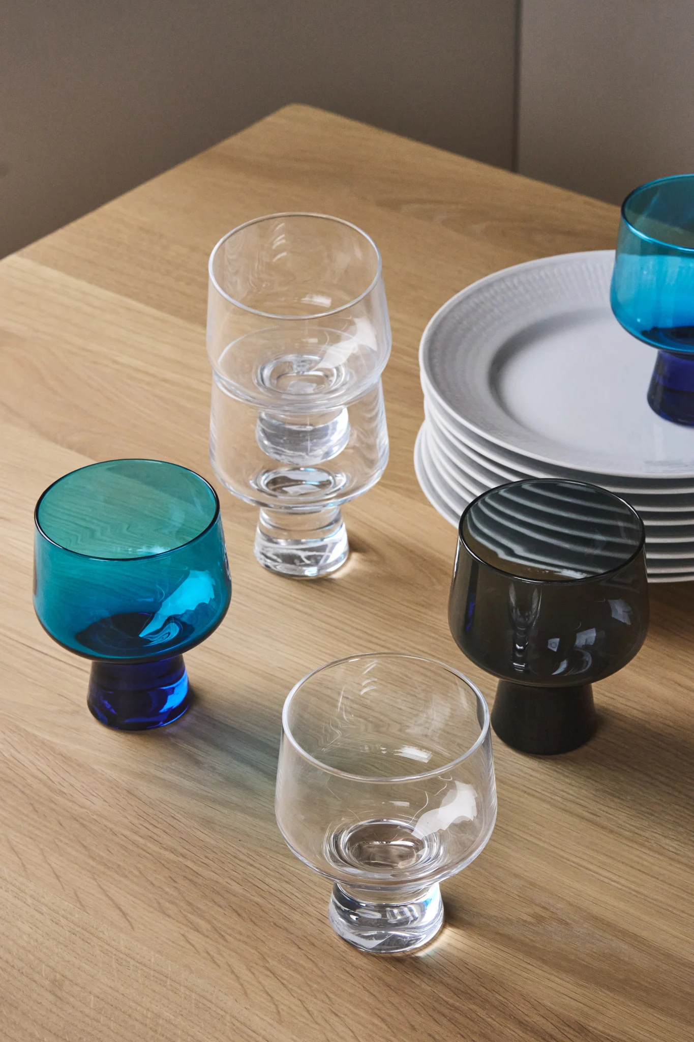 Here you see a collection of glasses from the Solare collection from Iittala along with a stack of white plates. 
