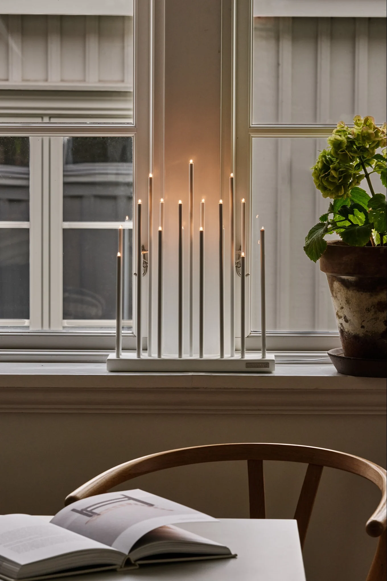 Minimalistic Christmas lighting from Elflugan, here you see the Elflugan candle arch in a window on a wooden sideboard. 