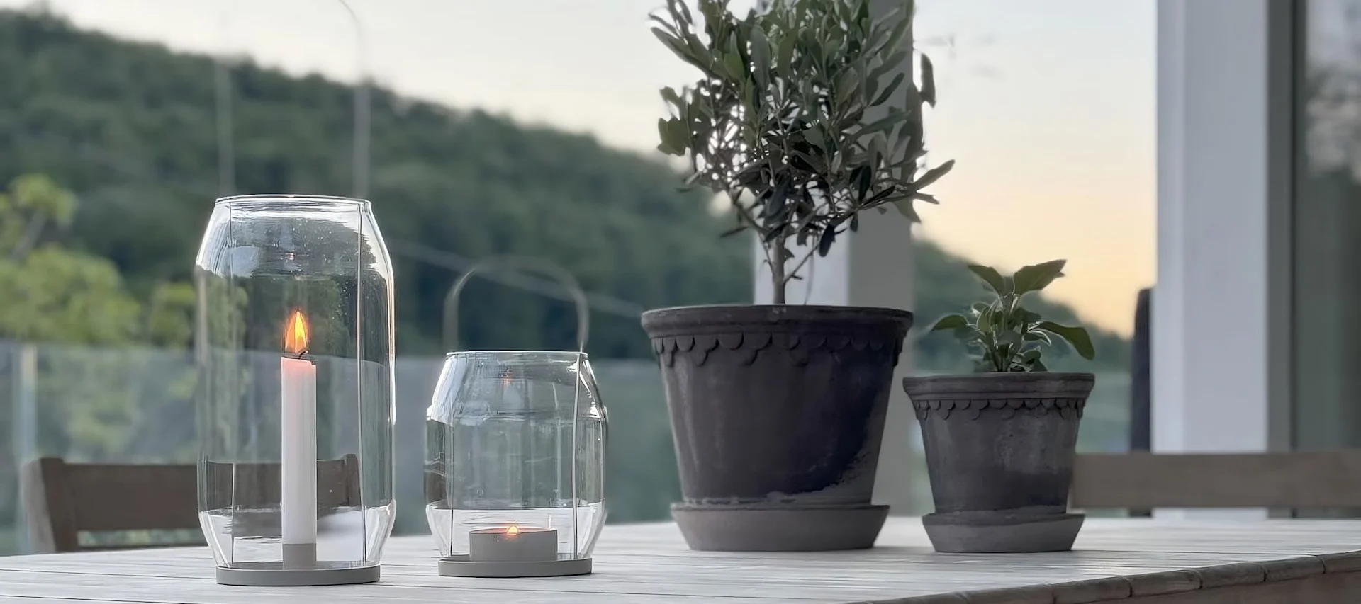 Two Copenhagen flower pots from Bergs Potter stand on a table, next to two Ernst lanterns on the terrace of @zuhauselig.