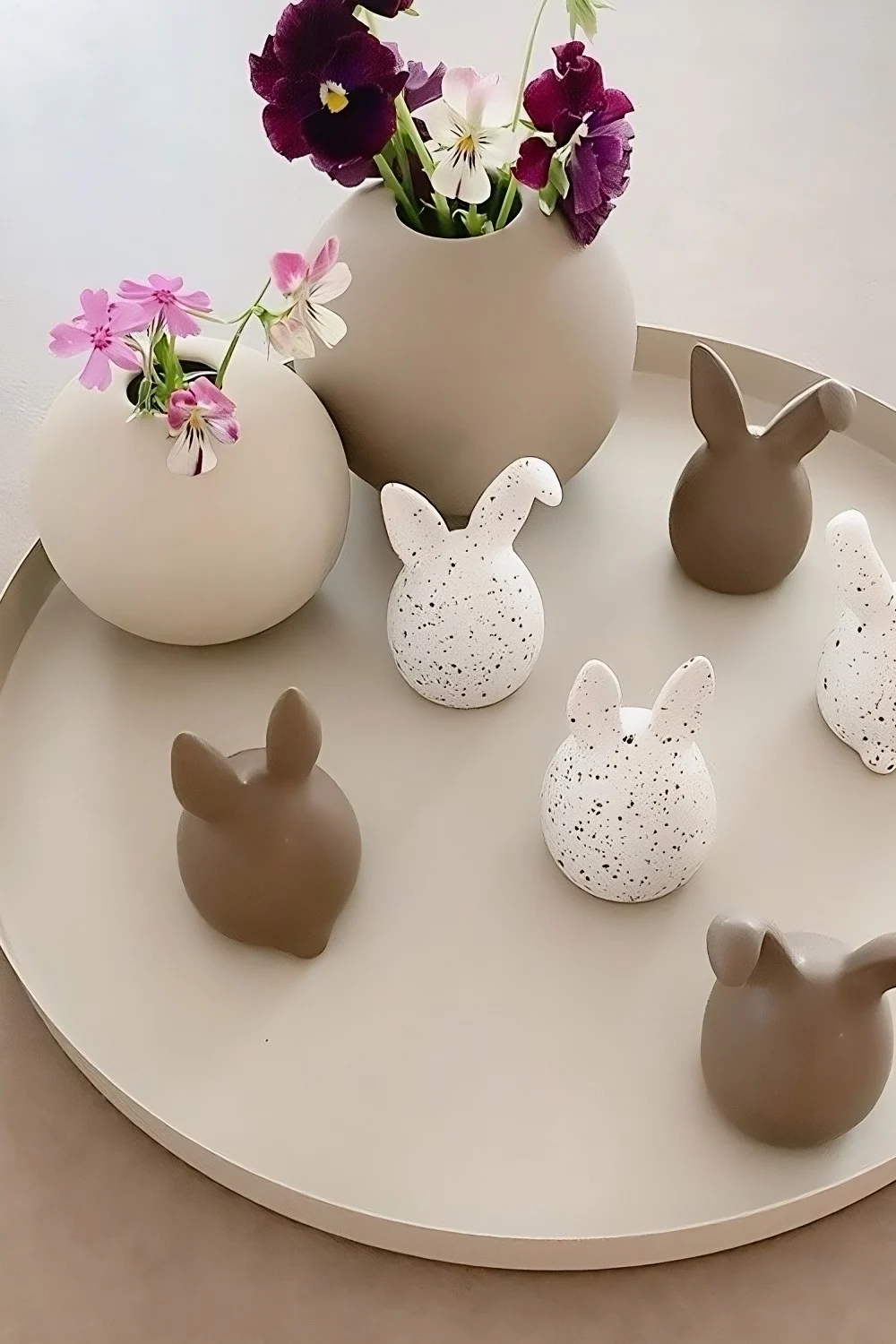 The triplets of Easter bunnies in two colours from DBKD stand on a tray, next to two ball vases from Cooee Design in @sachi_roooom's home.