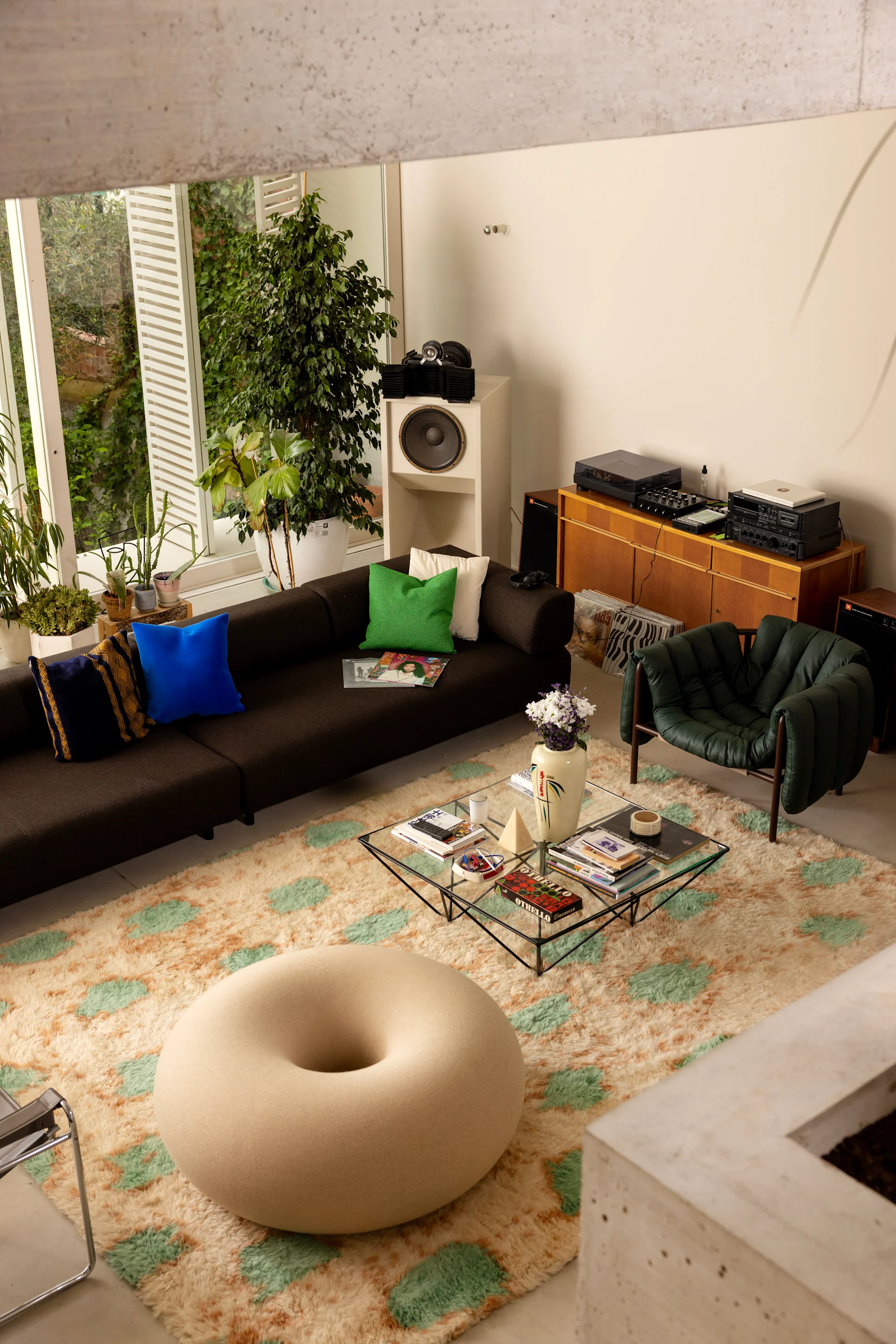 A doughnut-shaped, colorful pouf placed in a minimalist room with large windows captures the essence of 2026 interior trends, serving as a playful yet refined focal point.