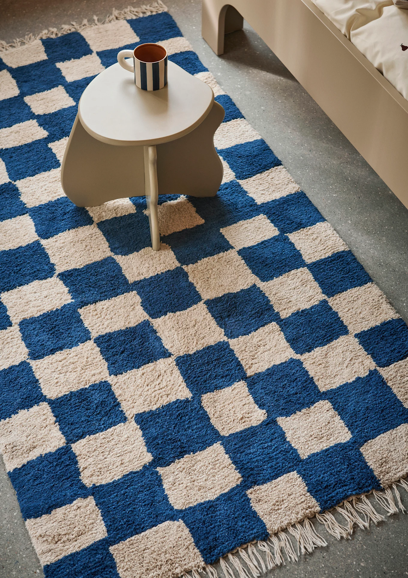 A side table stands on a blue and cream checked rug, the perfect idea for a children's room. 
