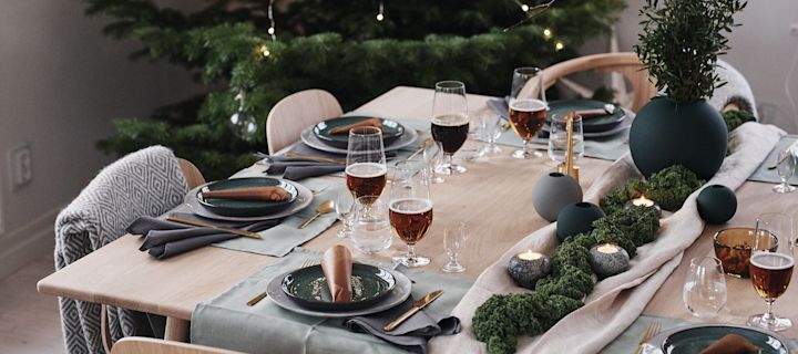 A green decorated Christmas table with kale and stylish dishes