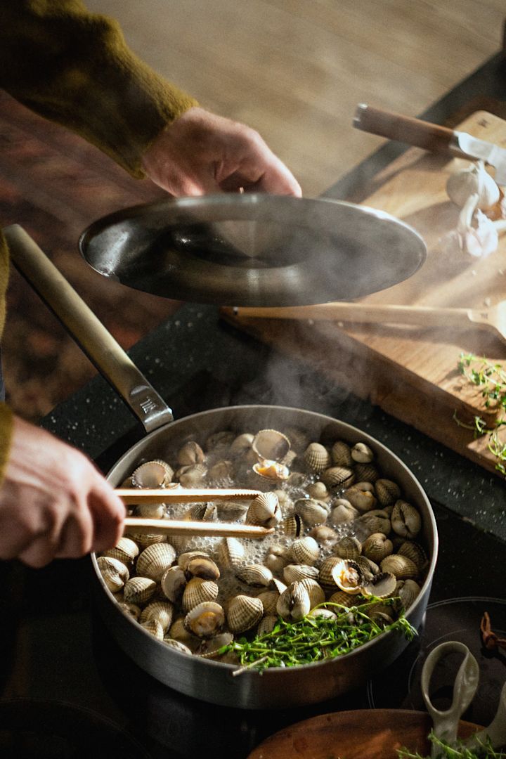 One person prepares mussels in the stainless steel Norden Steel sauté pan from Fiskars.